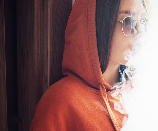 girl smokes vaporizer exhaling a lot of steam